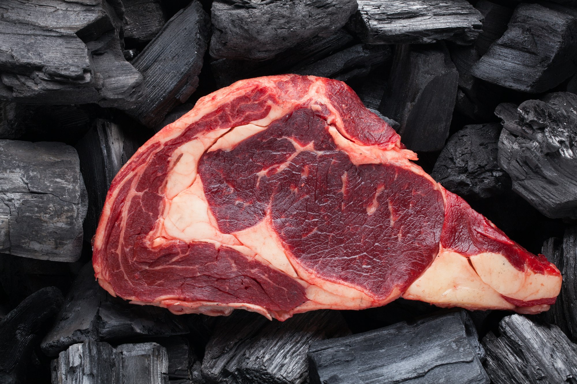 Raw fresh meat Ribeye steak on black charcoal background